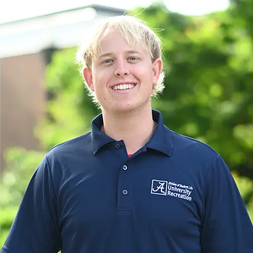 Smiling young man with blond hair wearing a navy blue